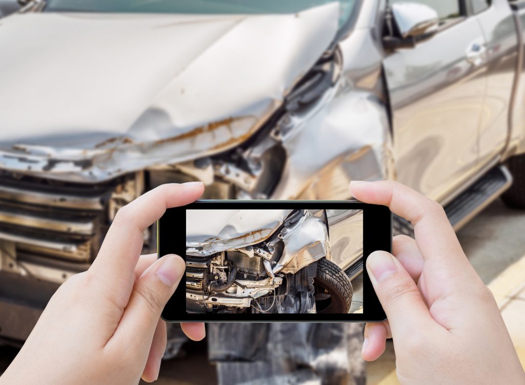 woman using mobile smartphone taking photo of car accident damaged for insurance